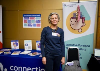 Victoria Bagnall from Connections in Mind CiC standing in front of the exhibitor stand. The banner in the background depicts Executive Functioning.